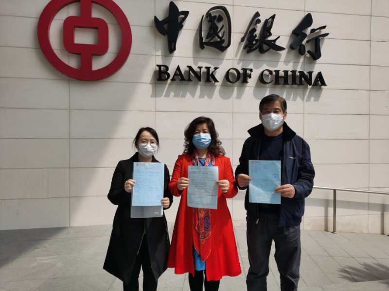 Chinese parents pose outside a bank after sending a cash donation to Duke Health.