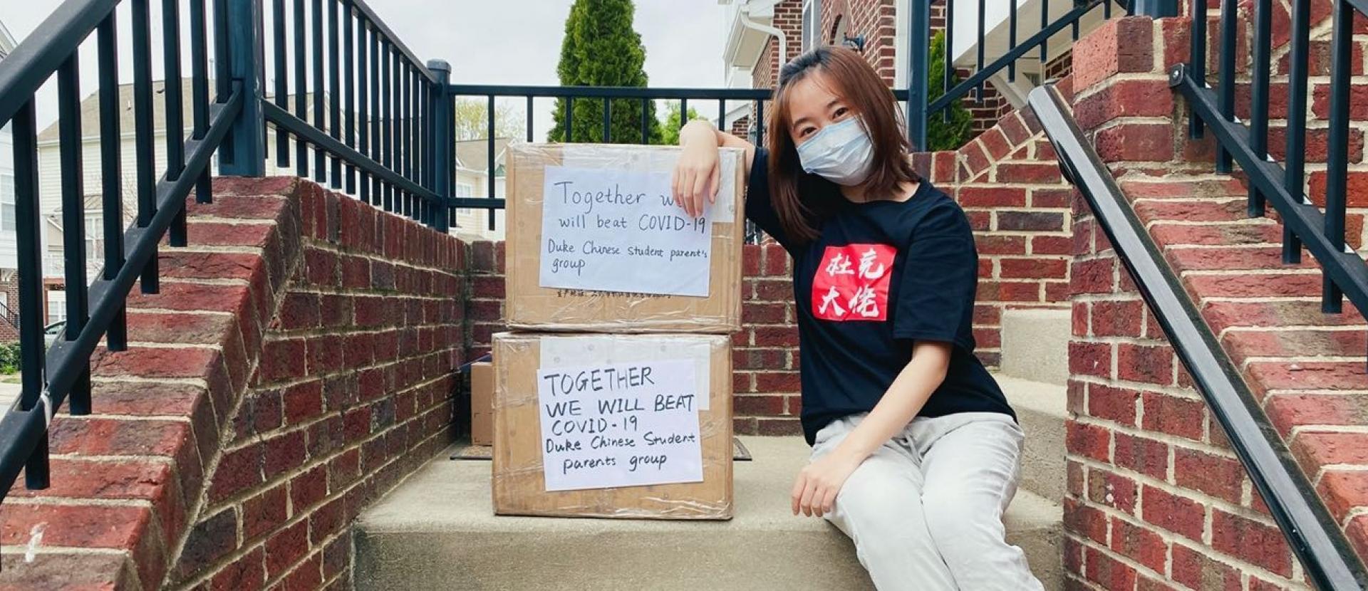 Chinese donor poses with personal protective equipment donated to Duke Health.