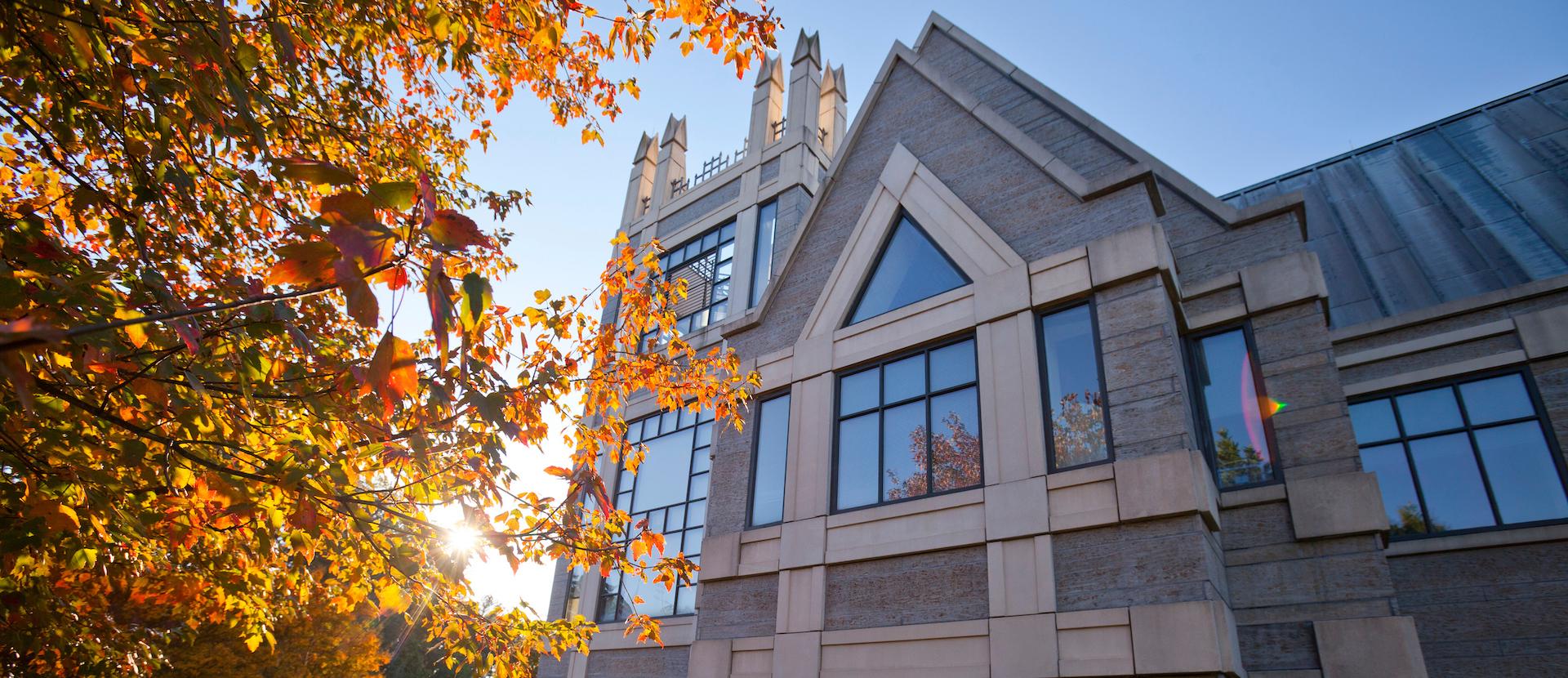 Landscape shot of the Sanford School of Public Policy with a blooming fall tree on the left.