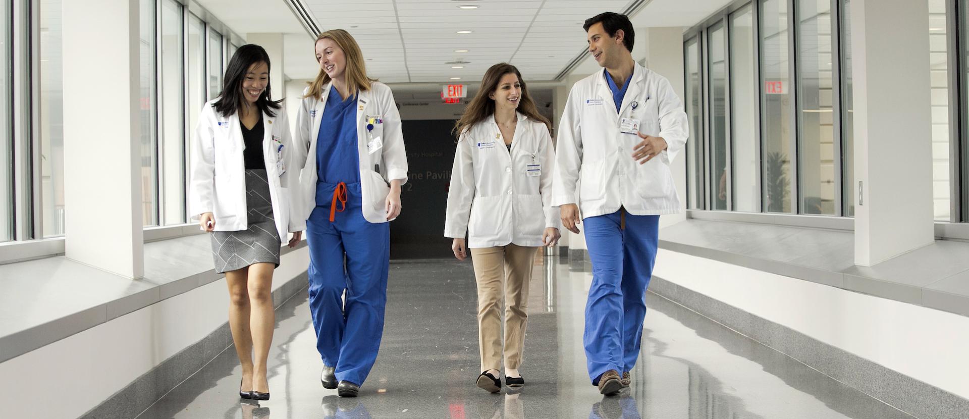 A group of four Duke Health caregivers walk down a hallway.