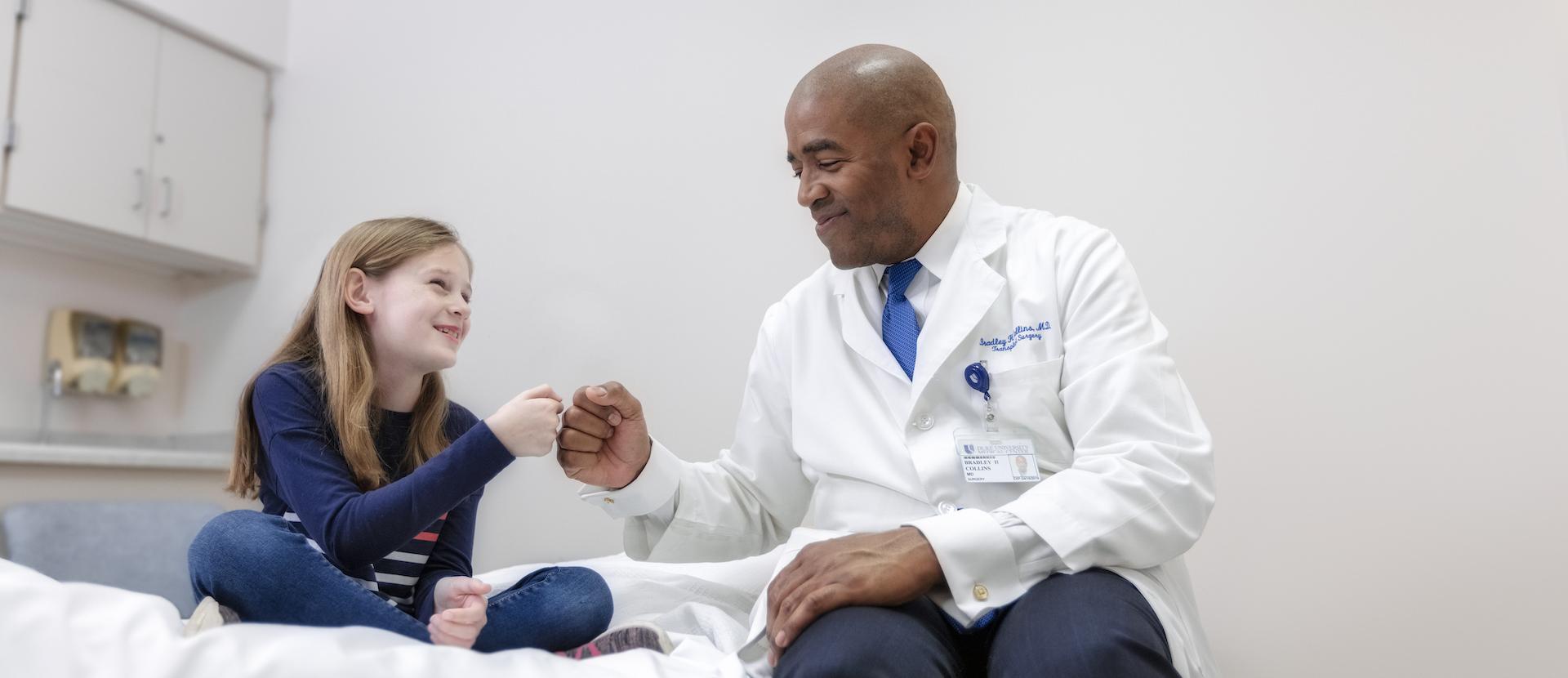 Duke doctor giving a fist bump to a young patient. 