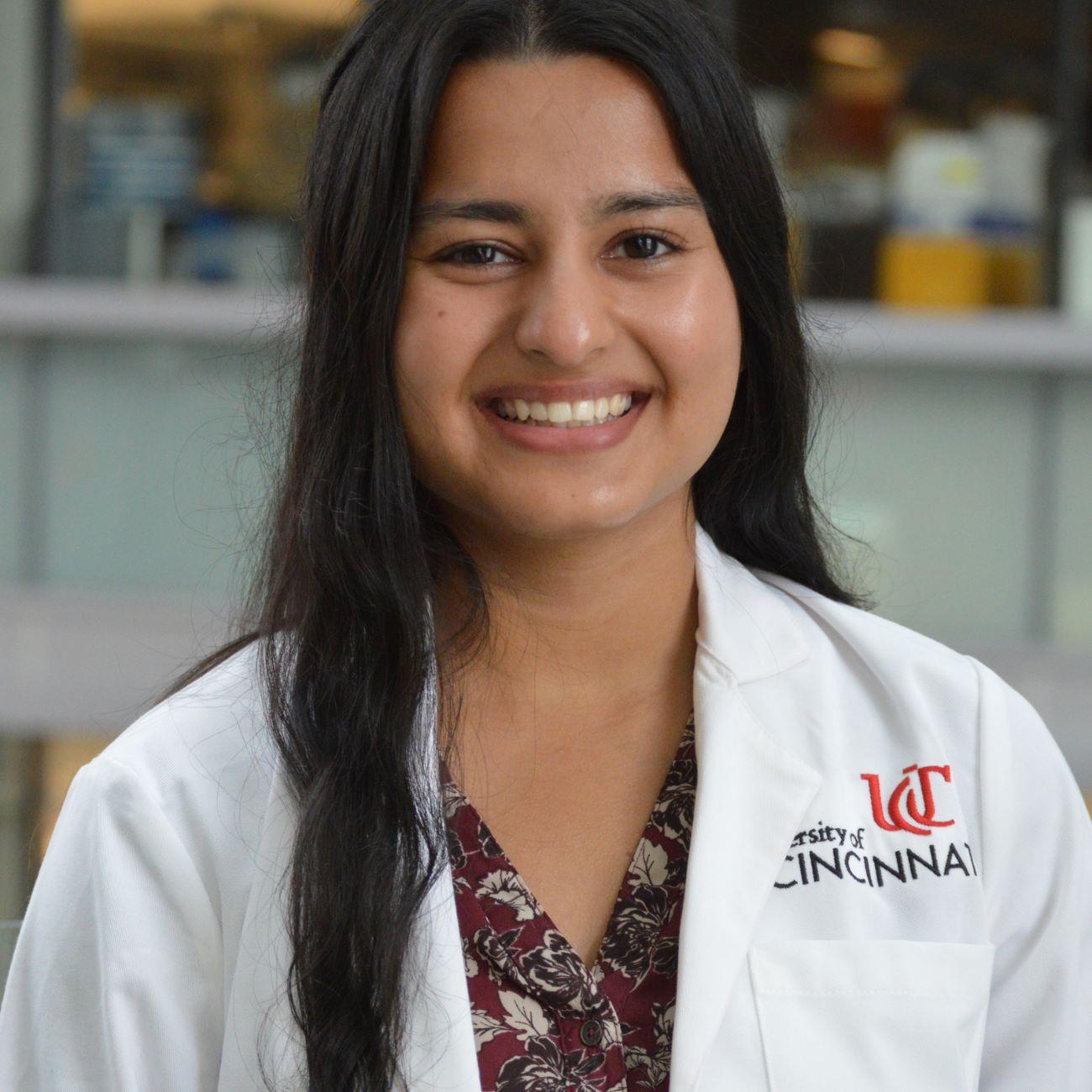 Sweta in a white coat is smiling for the picture.
