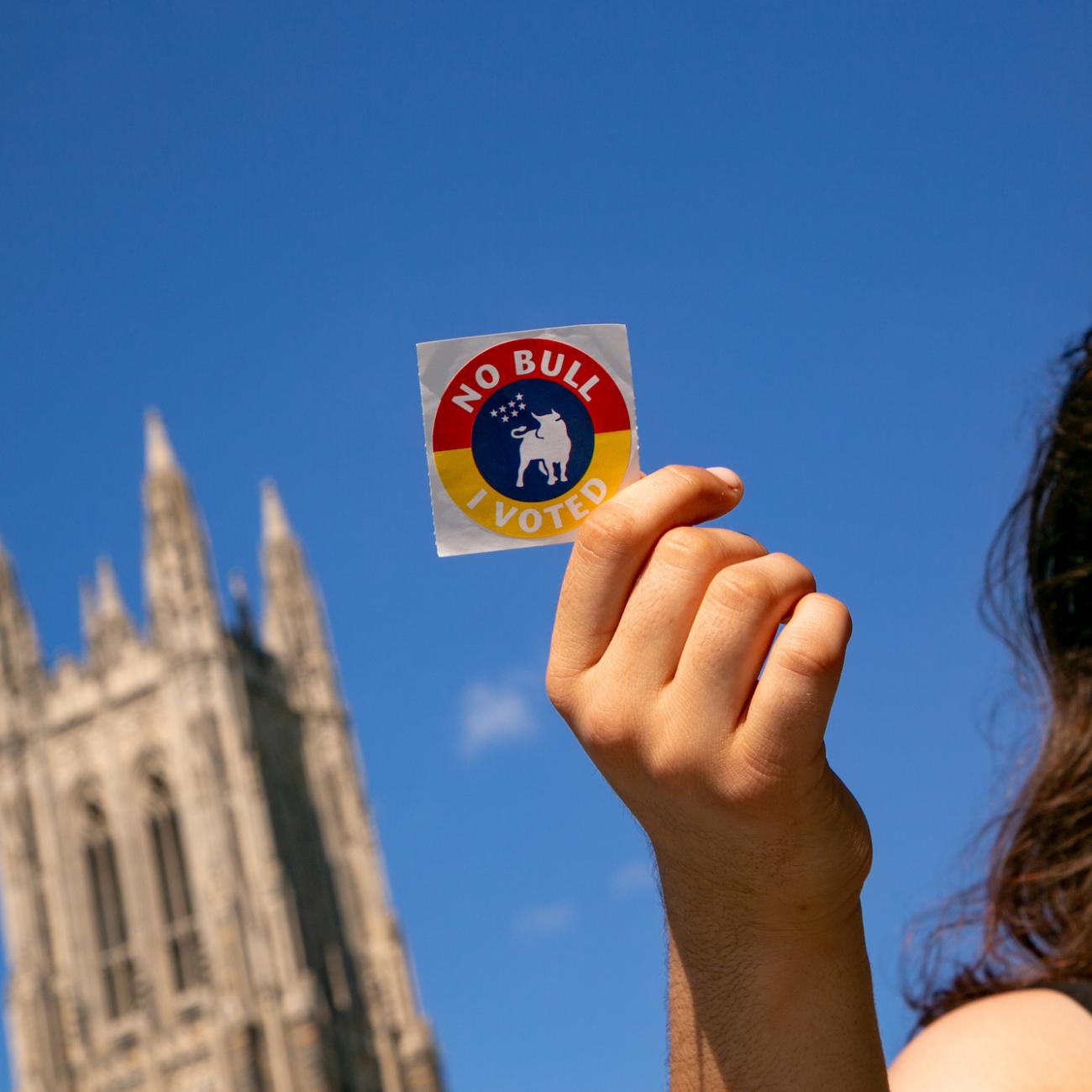 Woman holding voting sticker in front of Duke Chapel