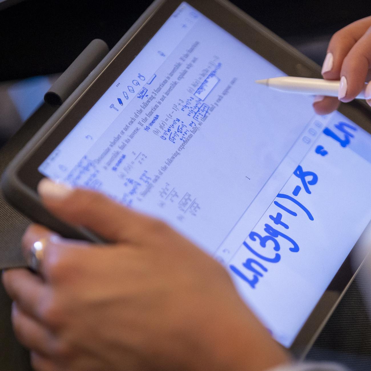 Close shot of student doing calculus equations on a digital tablet. 